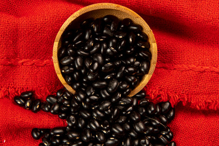 bowl of black beans falling onto red cloth, down viewの写真素材
