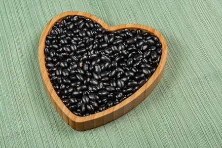 heart shaped black bean bowl on green tablecloth, top viewの写真素材