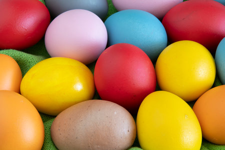 eggs painted in different colors to celebrate Easter on a green cloth backgroundの写真素材