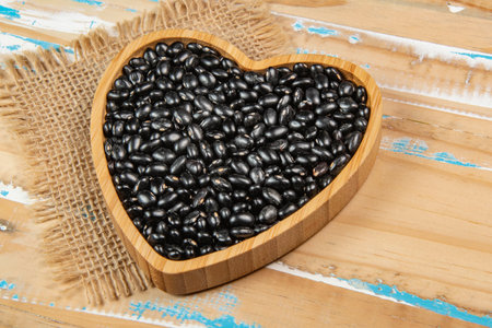 heart shaped black bean bowl on wooden table, top viewの写真素材
