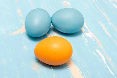 Eggs symbolizing the Easter holiday in blue and orange color on a background of aged wood in the same colorの写真素材
