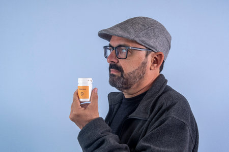 Mature man holding bottle of vitamin Dの写真素材