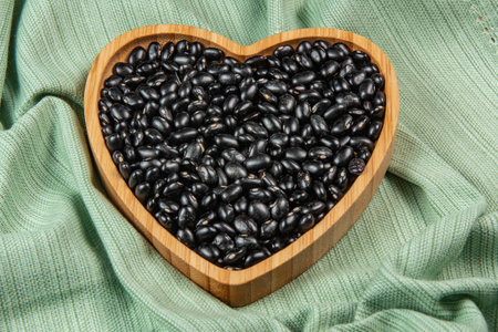 heart shaped black bean bowl on green tablecloth, top viewの写真素材