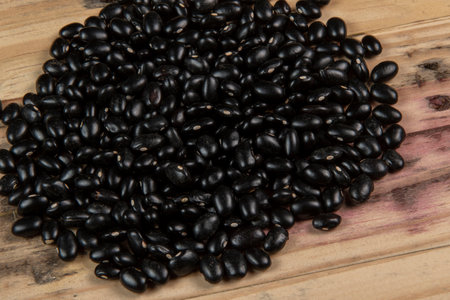 heap of black beans scattered over rustic wood, top viewの写真素材