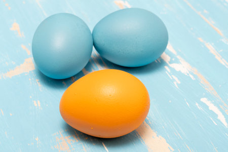 Eggs symbolizing the Easter holiday in blue and orange color on a background of aged wood in the same colorの写真素材