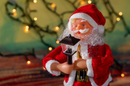 Santa claus doll with blurred christmas lights backgroundの写真素材