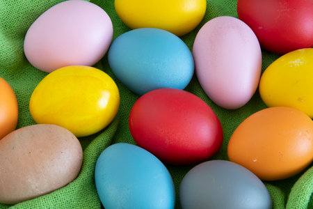 eggs painted in different colors to celebrate Easter on a green cloth backgroundの写真素材