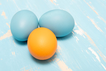 Eggs symbolizing the Easter holiday in blue and orange color on a background of aged wood in the same colorの写真素材