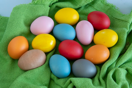 eggs painted in different colors to celebrate Easter on a green cloth backgroundの写真素材
