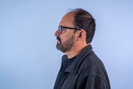 Portrait of a middle-aged man with glasses on blue backgroundの写真素材