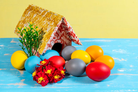colorful eggs symbolizing easter with a toy house and flowers like a gardenの写真素材