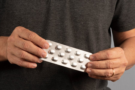 Unrecognizable men hands hold blister with pills, from different diseases. At home, indoors. high...