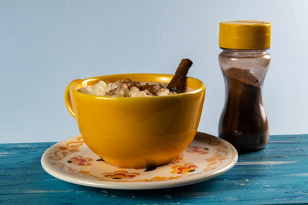 Typical Brazilian sweet dessert, Canjica. White corn porridge with cinnamon and coconut. Consumed at June festivals (festa Junina) on a rustic blue tableの写真素材