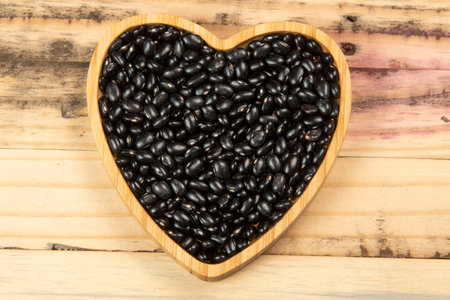 heart shaped black bean bowl on wooden table, top viewの写真素材