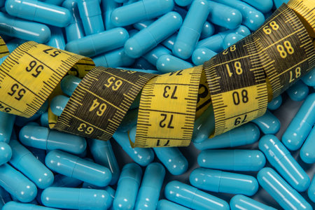 Weight loss blue gelatin pills and measuring tape symbolizing slimmingの写真素材