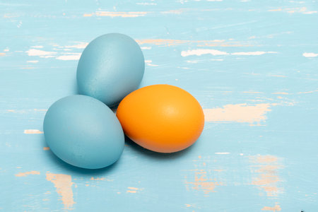 Eggs symbolizing the Easter holiday in blue and orange color on a background of aged wood in the same colorの写真素材