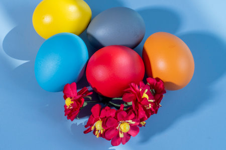 Colorful eggs symbolizing Easter on a colorful background and flowersの写真素材