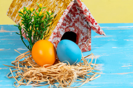 colorful eggs symbolizing easter with a toy house and flowers like a gardenの写真素材