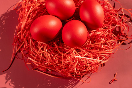 Colored eggs symbolize Easter in shades of red on strawの写真素材