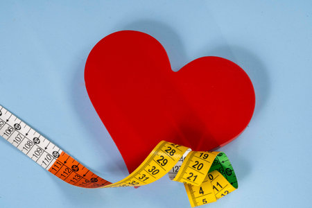 red heart shape with measuring tape symbolizing health care and exercise