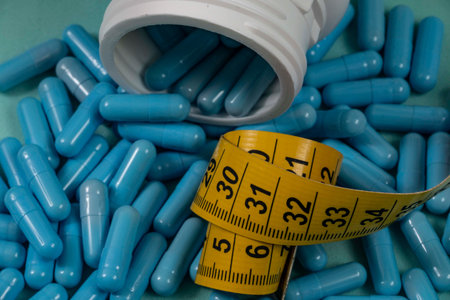 bottle of pills, some of which spilled onto a light blue surface, angled top view