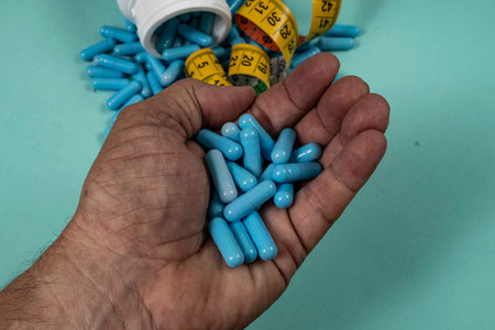 bottle of pills, some of which spilled onto a light blue surface, angled top viewの写真素材