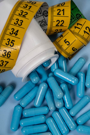 bottle of pills, some of which spilled onto a light blue surface, angled top viewの写真素材