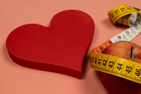Heart shape with an apple and measuring tape, concept of heart problem and excess body weightの写真素材