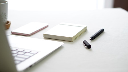 computer phone and notepad on the white background tableの写真素材
