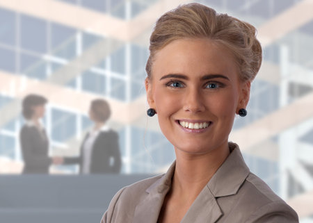 Closeup of a young, beautiful, and happy businesswoman in an office setting, smiling at camera
