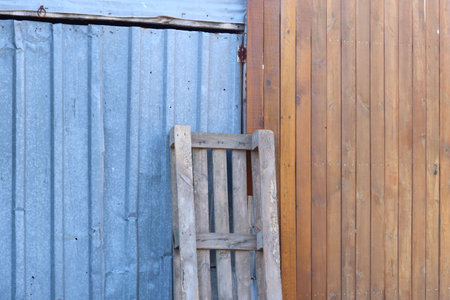 Wooden pallet standing in front of wooden fence and tin doorの写真素材