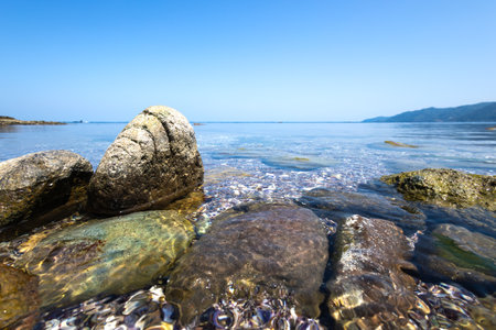 Rocky seashore with clear water and blue sky in summerの写真素材