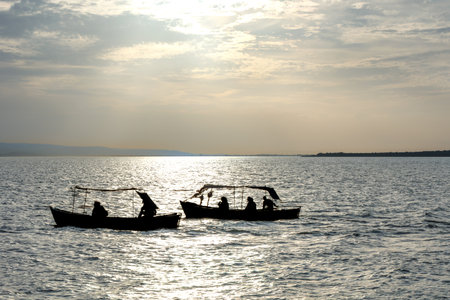 Silhouette of travelers in a boat on the lake in the evening.の写真素材