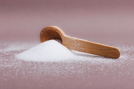 sugar in a wooden spoon on a pink background, close upの写真素材