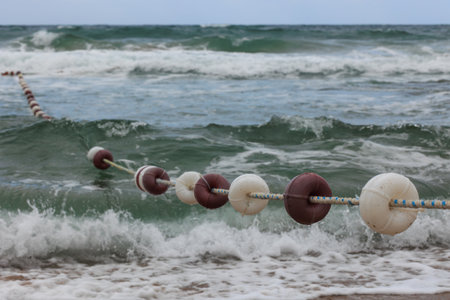 rope for the waves, close up of sea wave on beach and close up of a cable buoy on the beachの写真素材