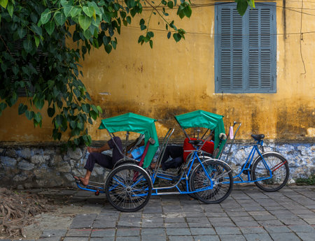 vietnamese men taking a nap on their bike in the street during work
