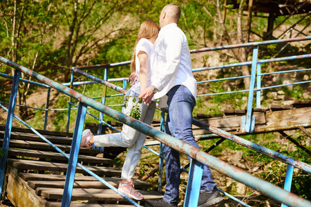 young hugging couple on stairs in green park