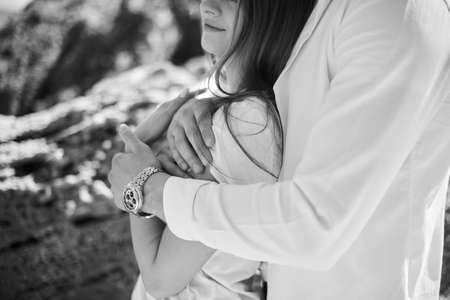 A young loving couple hugging and kissing on the beach in sunny day. Two lovers, man and woman near the water. Summer in love. Black and white photoの写真素材