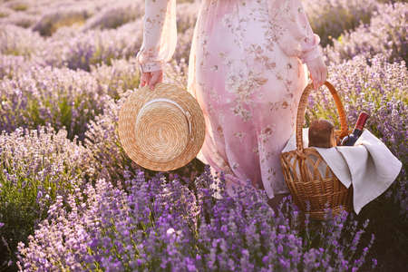 girl in the romantic dress with a straw hat in her hand looks for good place for picnicの写真素材