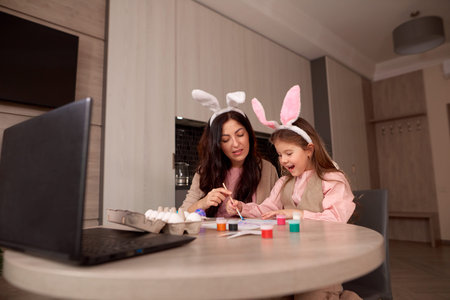 mom and daughter are watching YouTube internet videos how to paint eggs at home