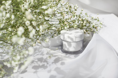 white cream jar side view. Organic cosmetology, natural cosmetics. Facial, body balm plastic container and foliage compositionの写真素材