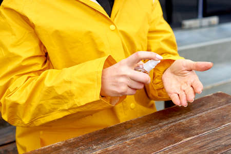 Coronavirus. Woman use spray sanitizer on hand in street. transparent antiseptic in hands in streetの写真素材