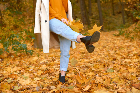 woman in stylish casual clothes kicks leaves in the park. shallow depth of field