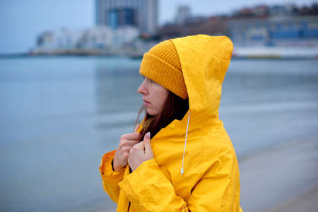 Portrait of pensive woman in yellow coat on the beach in winterの写真素材