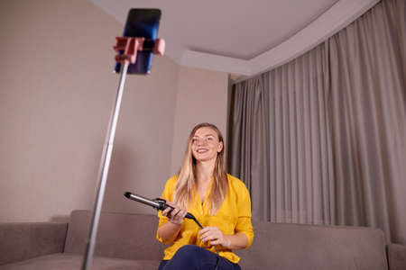 beautiful woman hold curling iron and records online training how to quickly and easily do styling at homeの写真素材
