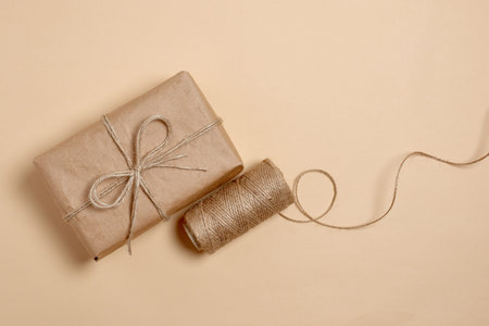 Packing order with recycling material. kraft paper gift on beige background. eco box gift with twine...