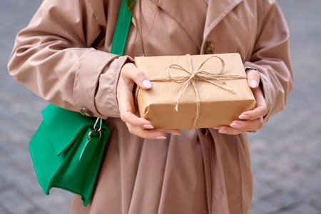 close up view woman's hands holding a gift box at the street