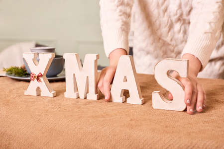 woman decorate with xmas letters festive table. owner setting table in little shop for happy holiday saleの写真素材