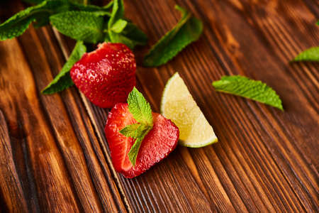 lime strawberry mint ingredients for making lemonade on white plate on wooden tableの写真素材