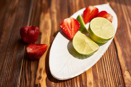lime strawberry mint ingredients for making lemonade on white plate on wooden tableの写真素材